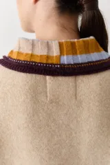 Buzo de lana tipo polo con cuello y cartera de botones en colores contrastantes. Presenta mangas con textura de ochos y puños y ruedo con terminaciones en franjas de colores.