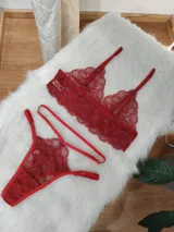 Conjunto de lencería de encaje color rojo, compuesto por un bralette triangular con breteles regulables y una tanga con tiras laterales ajustables.