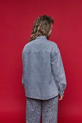 Sobrecamisa de jean de calce relajado color gris, con solapa clásica, bolsillos frontales y cierre de botones metálicos.