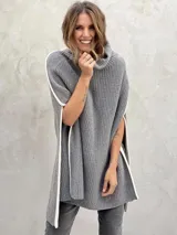 Poncho gris de lana con cuello alto y aberturas laterales con ribete blanco.