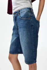 Bermudas de cinco bolsillos en denim de algodón rígido, con talle alto, cierre de cremallera y botón.