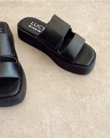 Sandalias negras de cuero vacuno con plataforma y tiras regulables con velcro.