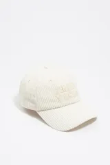 Gorra de pana color crema con visera curva y logo de la marca bordado en el frente.
