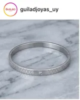 Esclava rígida de acero inoxidable con textura grabada en forma de rombos y una circonia incrustada en el centro.