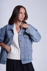 Campera clásica de jean celeste con cuello camisero, bolsillos frontales con solapa y cierre con botones metálicos. Presenta detalles de pequeños brillos blancos dispersos en la parte delantera y las mangas.