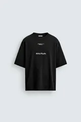 Remera de corte holgado confeccionada en algodón con interior de tejido rizo. Presenta cuello redondo, manga corta y estampados con texto en contraste en la parte frontal.