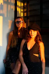 Vestido corto negro con estampado de plumas doradas, escote en V, breteles finos cruzados en la espalda, cut-outs laterales y volado en el ruedo.