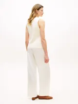 Chaleco slim de punto de puro algodón peinado, color blanco, con cuello en V, cierre frontal de botones dorados y logo bordado en la parte inferior.
