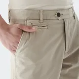 Pantalón chino color beige, de corte recto, con bolsillos laterales y traseros. Se ajusta a la cintura con cinturón de cuero marrón.