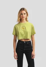 Remera cropped de algodón, color gris claro, con cuello redondo y manga corta doblada. Presenta un estampado frontal de un plátano amarillo.