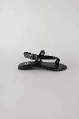 Sandalias planas color negro, de cuero, con tiras en el empeine decoradas con tachas metálicas plateadas, tira ajustable con hebilla en el talón y diseño de dedo.