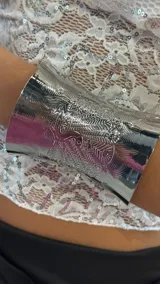 Brazalete ancho plateado con diseño grabado.