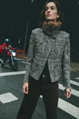 Chaqueta de tweed en tonos gris y negro, con cuello desmontable de pelo sintético marrón, bolsillos delanteros de plastrón y acabados deshilachados.