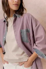 Camisa de denim color verde menta con calce relajado, cuello clásico, cierre frontal con broches metálicos, mangas largas y bolsillo aplicado en el pecho, con detalles en tono gris azulado a contraste en cuello, cartera, bolsillo y puños.