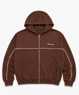 Campera con capucha marrón de corte boxy, con cierre frontal completo y bolsillos estilo canguro. Presenta una línea blanca horizontal en el pecho que se extiende por las mangas y un pequeño logo bordado.