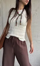 Blusa de punto sin mangas en color natural, con textura fruncida en todo el diseño y cuello redondo.