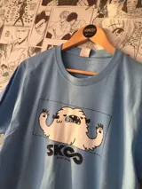 Remera celeste con estampado de un monstruo de nieve blanco y el logo de la serie Sk8: The Infinity.