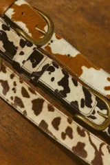 Cinto de cuero vacuno con pelo natural, con hebilla metálica y costuras reforzadas.