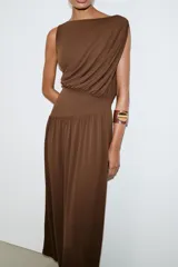 Vestido largo sin mangas de cuello redondo, confeccionado en tejido drapeado con detalle de cintura tipo fajín en el mismo material.