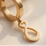Caravanas de acero dorado con diseño de símbolo de infinito colgante.