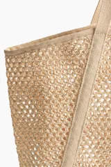 Bolso de playa de red color beige, confeccionado en paja plástica con dos asas largas y base rígida.