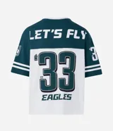 Remera de corte oversized con diseño deportivo de los Philadelphia Eagles. Presenta cuello redondo, mangas cortas con detalles de rayas y estampa frontal del equipo. Confeccionada en algodón.