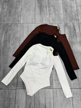 Body de manga larga con diseño de hombros descubiertos y detalle de herraje metálico dorado en el escote. Confeccionado en tela elástica, disponible en colores blanco, negro y marrón.