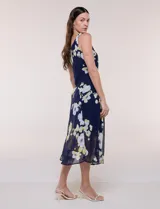 Conjunto de dos piezas en gasa azul marino con estampado floral en tonos blancos y amarillos, compuesto por un vestido midi sin mangas con forro y una capa ligera de mangas amplias.