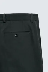 Pantalón de corte regular fit confeccionado en tejido mezcla de algodón. Presenta cintura con detalle de pliegues en el delantero, bolsillos frontales y bolsillos traseros de vivo con botón. Cierre frontal con cremallera y botón.