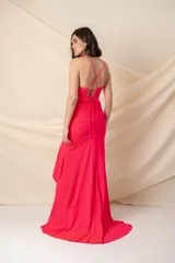 Vestido largo color fucsia con breteles finos cruzados en la espalda, escote en V, drapeado en la cintura, volados desde la cintura y abertura lateral. Presenta un poco de cola.