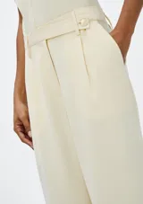 Pantalón recto de tiro alto color marrón, con pinzas delanteras, trabillas para cinturón y cierre frontal oculto.