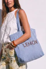 Maxi bolso tipo tote bag de algodón, con diseño de rayas verticales en color azul y blanco. Presenta asas largas para llevar al hombro y el nombre de la marca 'LEMON' impreso en el frente.