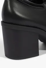 Zapato tipo Oxford de cuero negro con cordones, ojales metálicos dorados y taco ancho.