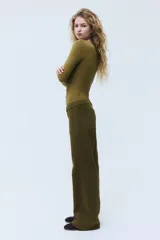 Pantalón de sarga de algodón verde militar, con piernas rectas y tiro medio. Presenta cierre con botón, bolsillos delanteros de parche conectados a las trabillas y bolsillos traseros también de parche.