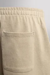 Short jogger marrón de corte relaxed fit, confeccionado en tejido compacto de algodón, con cintura elástica ajustable, bolsillos frontales en la cadera y bolsillo trasero de plastrón.
