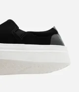 Championes slip on negros con efecto gamuza, suela alta blanca y detalle croco en el talón.