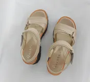 Sandalias bajas color beige con tiras anchas de cuero, ajuste con hebilla y suela track color negro.