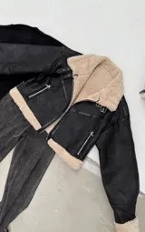 Chaqueta corta tipo aviador confeccionada en símil gamuza color negro con forro y ribetes de corderito en contraste. Presenta cierre frontal metálico, cuello de solapa y detalles en cuero sintético.