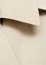 Chaqueta corta tipo trench color beige, con cuello de solapa, cierre de doble botonadura y manga larga. Cuenta con forro interior y diseño recto.