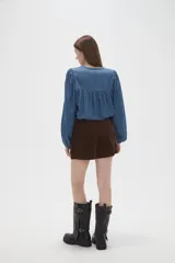 Short de tiro alto confeccionado en pana color marrón, con diseño de botones decorativos en la cintura y corte recto.