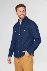 Camisa de jean celeste de manga larga, con cuello clásico, cierre frontal con botones a presión, dos bolsillos con solapa abotonada en el pecho, corte en hombros y detalle en la espalda.