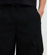 Bermuda cargo baggy negra, confeccionada en poliéster con cintura elástica, cordón ajustable y bolsillos laterales con cierre de cremallera.
