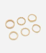 Set de seis anillos dorados con diferentes diseños: uno liso con strass, uno trenzado, uno con forma de onda y tres lisos.