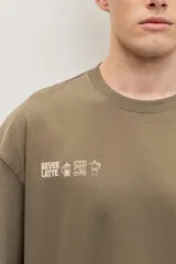Remera de corte oversize color blanco tiza, de manga corta y cuello redondo, con pequeño estampado gráfico azul en el pecho.