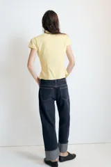 Jeans rectos de tiro medio en denim negro con efecto lavado. Presenta diseño de cinco bolsillos, trabillas para cinto y bajo con vuelta marcada. Cierre frontal con botones metálicos ocultos.