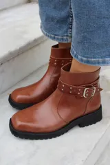 Bota corta de cuero azul con suela track negra, detalle de tira con hebilla metálica y tachas decorativas en el tobillo.