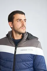 Campera inflada de abrigo para hombre, con capucha desmontable, cierre frontal completo, bolsillos con cierre y logo estampado. Diseño color block en azul, blanco y gris.