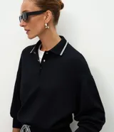 Buzo cerrado de algodón con cuello polo, mangas largas con puños ajustados y detalle de líneas contrastantes en el cuello.