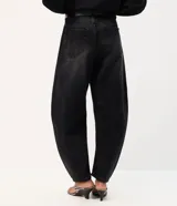 Pantalón baggy balloon de jean negro, tiro medio, con calce amplio, recortes estructurales y botamanga ajustada. Incluye bolsillos delanteros y traseros, y un cinturón de PU negro con hebilla metálica circular.