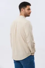 Camisa de lino y algodón color blanco, con cuello mao, manga larga y cierre frontal de botones. Presenta un pequeño logo bordado en el pecho.